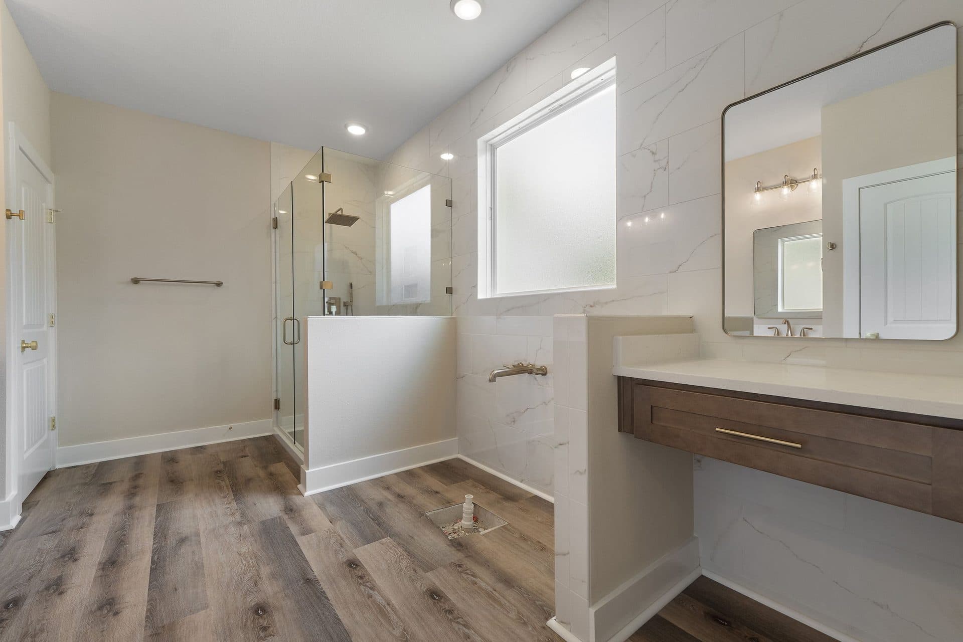 The Ashley primary bath with a frameless glass shower in marble-look tile and a makeup vanity