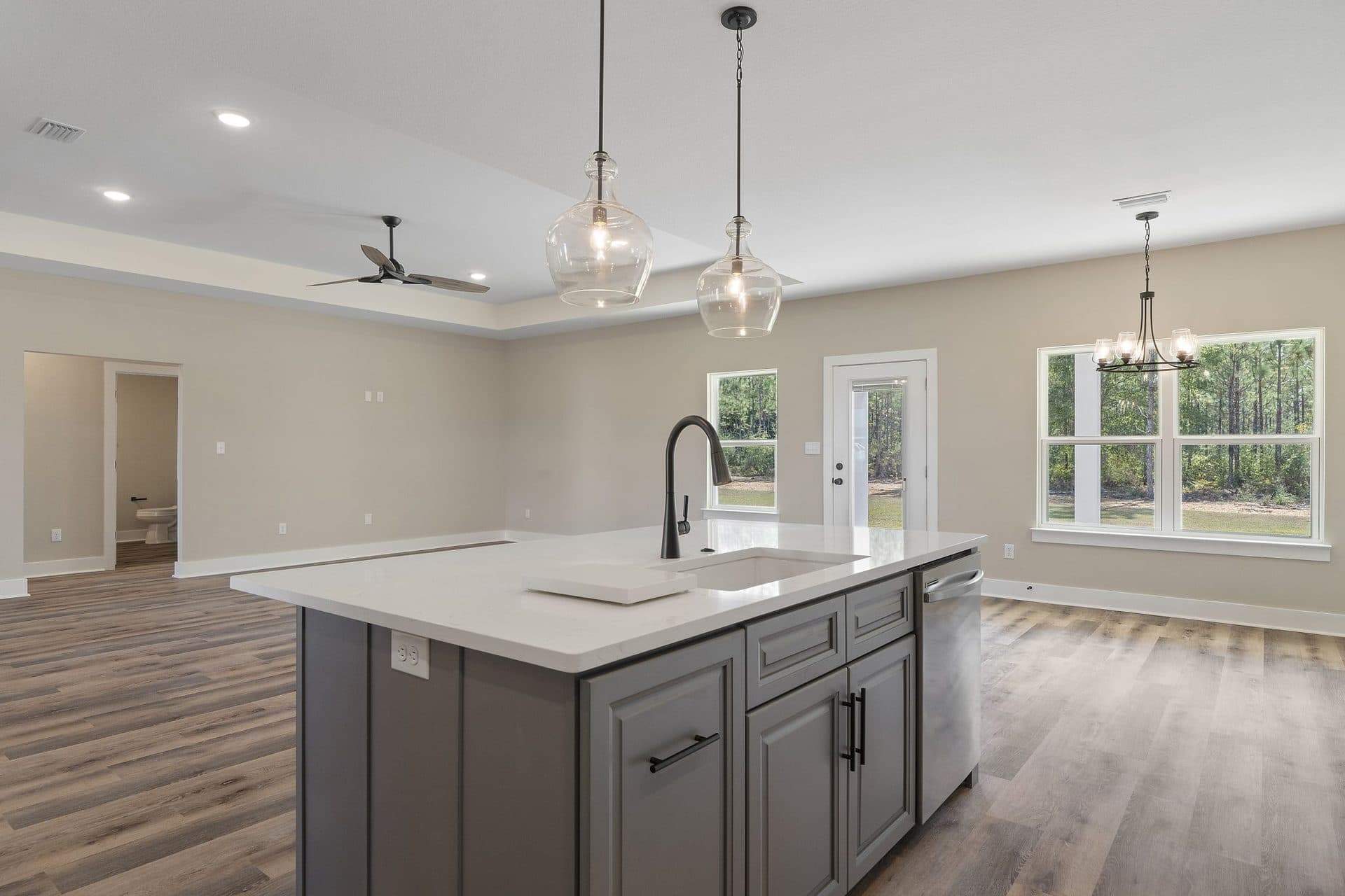 The grey kitchen island with a matte black faucet in a finished Lunsford, looking out to the dining area