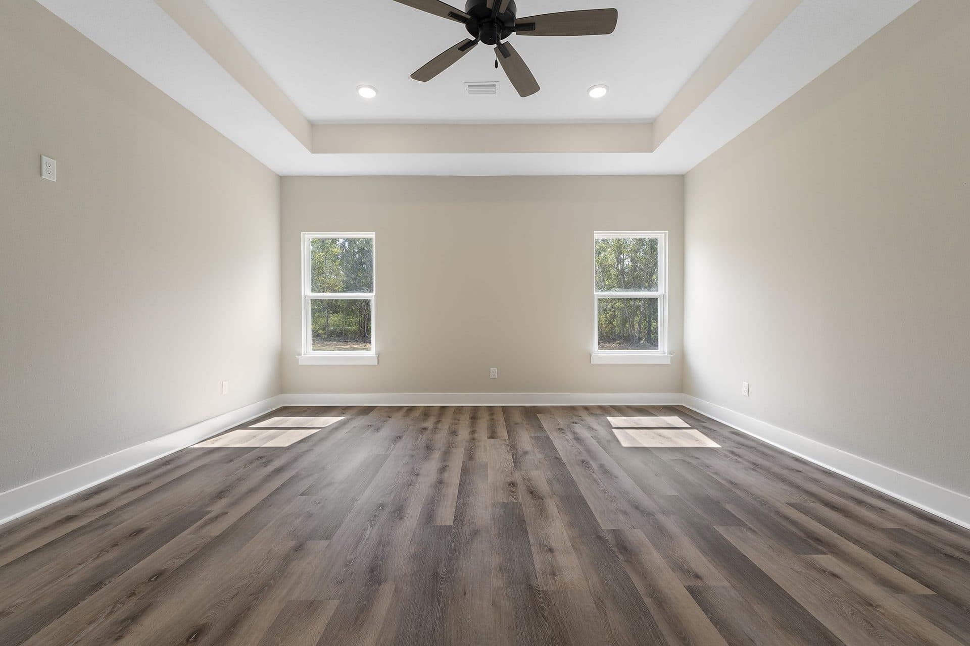 The primary bedroom of a finished Lunsford with a tray ceiling